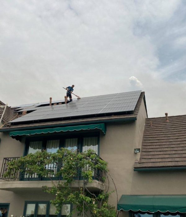 A Big Wave Window service technician solar panel cleaning on a roof